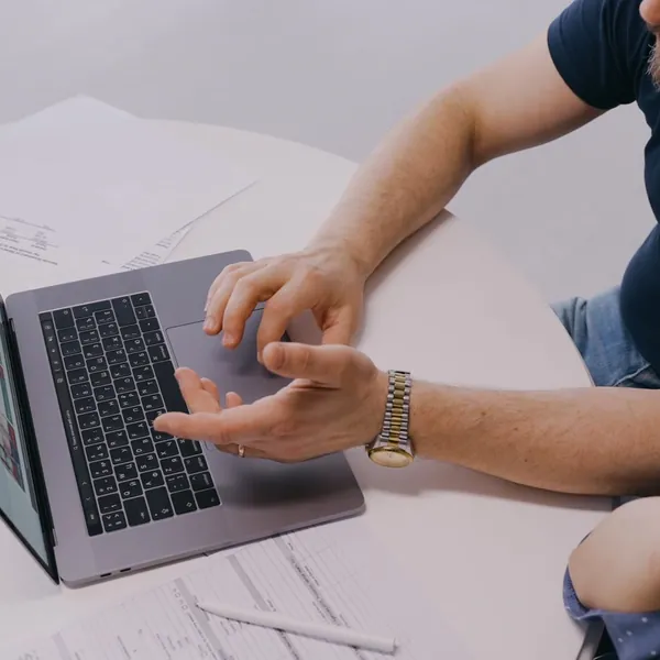 Pessoa apresentando um site em um notebook sobre a mesa