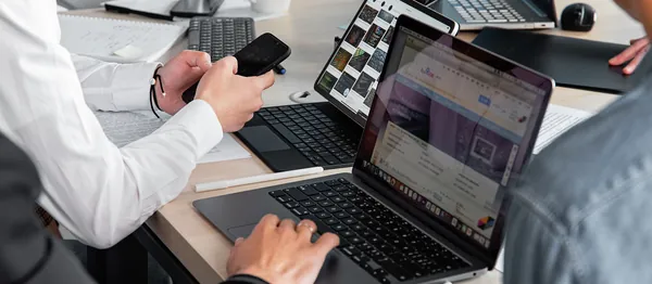 Pessoas trabalhando em notebooks em uma mesa de escritório